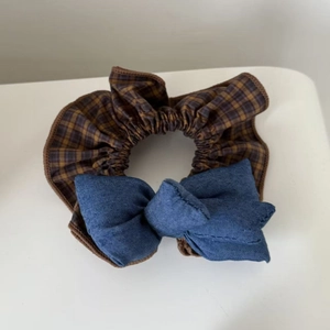 Close-up of retro blue denim and yellow plaid bow scrunchie with soft ruffled fabric texture