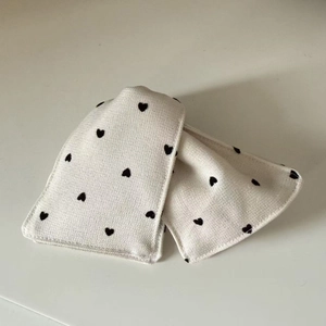 Close-up of cream knit hairband with embroidered black heart patterns and soft texture