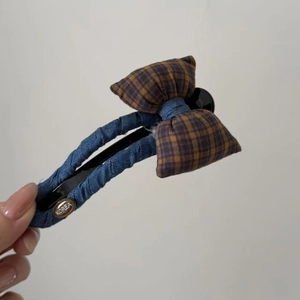 Detail of blue denim and orange plaid bow hair clip with engraved Korea metal tag