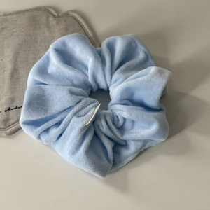 Soft light blue velvet scrunchie with fluffy pleated texture for elegant ponytail styling
