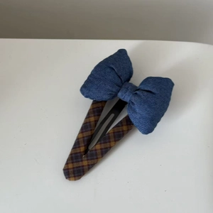 Detail of blue denim bow hair clip with vintage plaid fabric wrap and metal BB clip base
