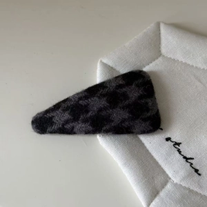 Close-up of black and grey houndstooth wool BB clip on minimalist white fabric