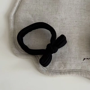Detail of a black ribbed fabric hair tie featuring a minimalist vintage bow decoration