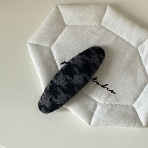 Close-up of oval houndstooth fabric hair clip for women with warm autumn texture