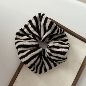 Striped knit scrunchie with black and white texture on a premium velvet display tray