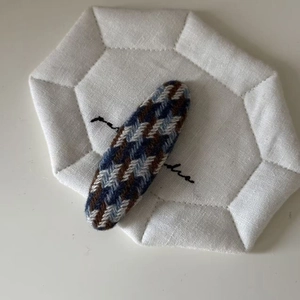Detail showing the elegant tweed houndstooth texture of the oval blue and brown hair clip