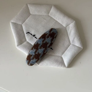 Close-up of brown and blue houndstooth weave fabric BB hair clip on a quilted mat