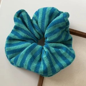Detailed close-up of blue and green striped knit scrunchie with soft ribbed wool texture