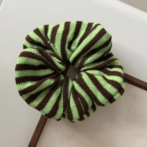 Detail of oversized striped knitted scrunchie in green and coffee brown colors