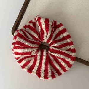Detailed close-up of red and white striped knitted scrunchie on a wooden display tray