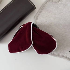 Detail view of large burgundy velvet hair claw clip with white piping on fabric edges