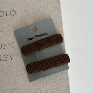 Close-up of brown twill knit hair clips set on a display card for minimalist hair styling