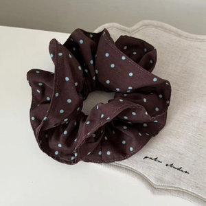 Close-up of vintage brown chiffon scrunchie with light blue polka dots on white desk