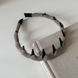 Cerchietto retrò in maglia a coste grigie con denti antiscivolo su sfondo di un libro