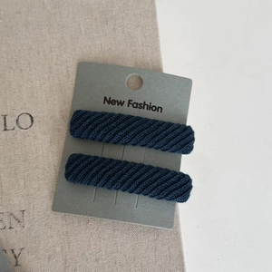 Close-up of dark blue ribbed twill hair clips on a New Fashion display card