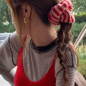 Striped knit scrunchie with red and white patterns worn on a casual braided hairstyle