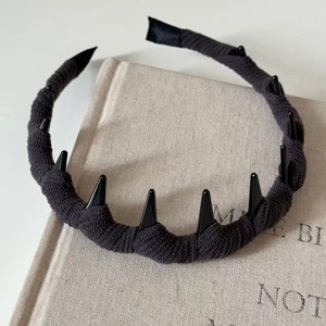 Dettaglio di cerchietto nero in maglia con borchie punk lucide su tessuto strutturato