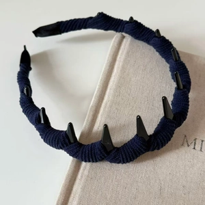 Dettaglio cerchietto in maglia blu scuro con nove borchie decorative nere stile punk