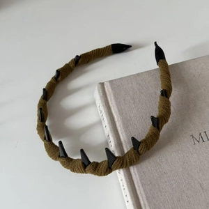 Dettaglio del cerchietto intrecciato verde oliva con accenti di punte nere punk