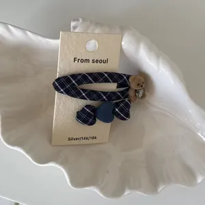 Détail de barrettes à cheveux à carreaux avec un ours en peluche et un cœur en strass