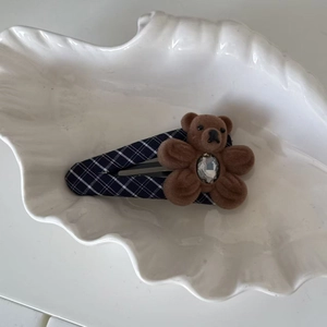 Détail de la pince à cheveux à carreaux avec un ours floqué et un cristal en cœur