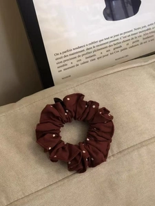 Haargummi aus burgunderrotem Satin mit Punkten auf minimalistischem beigem Leinenhintergrund