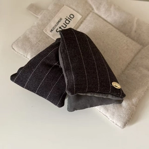 Maillard striped fabric hair claw clip with golden metal logo on grey felt background