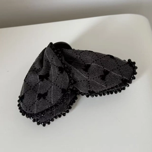 Detail of grey plaid hair bow with black beaded edges and elegant embroidery