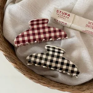 Detail of red and black checkered acetate hair claws on soft fabric and woven basket