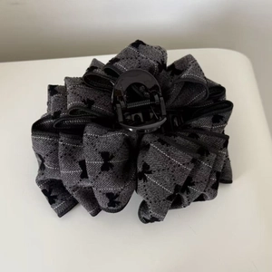 Detail view of large grey plaid fabric claw clip with elegant black bow design