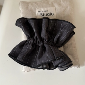 Macro detail of dark grey striped fabric hair scrunchie with pleated elastic texture