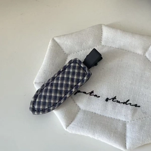 Detailed macro view of a plaid fabric duckbill hair clip with neat stitching details