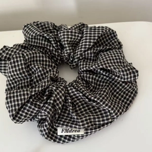 Elegant black and white plaid scrunchie with soft fabric texture and woven brand label