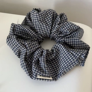Blue and white plaid scrunchie with minimalist fabric label on white background