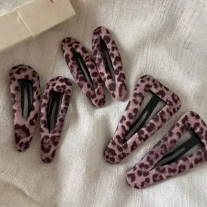 Close-up of pink leopard print BB hair clips in teardrop and triangle shapes on linen