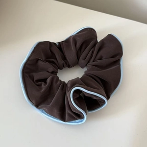 Detailed view of dark brown scrunchie with light blue silk piping and pleated texture