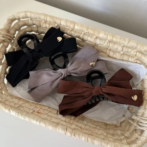 Trois pinces à cheveux à nœud en suédine noire grise et marron avec cœurs dorés