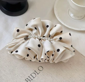 Détail d'une pince à cheveux vintage à pois avec perles élégantes sur tissu en soie
