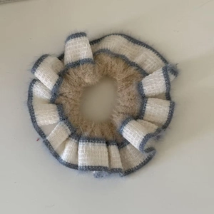 Detailed macro view of khaki plush fabric with gray-white striped pleated edges scrunchie
