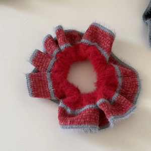 Detail of red and gray knitted scrunchie with soft plush texture for winter hair styling
