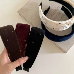Polka dot velvet headbands in various colors on a minimalist desk with vintage book decor