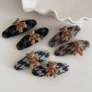 Detail view of 6-piece plaid bear hair clips with flocking texture and red bow accents