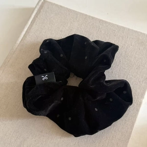 Détail d'un chouchou en velours noir à pois avec une texture douce et élégante