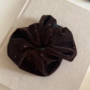 Détail d'un chouchou en velours marron foncé à pois beige avec texture plissée élégante