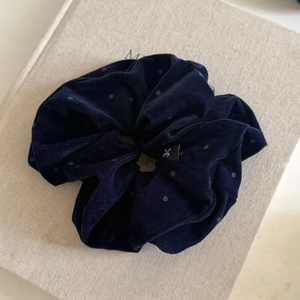 Détail d'un chouchou en velours bleu marine à pois avec petite étiquette tissée