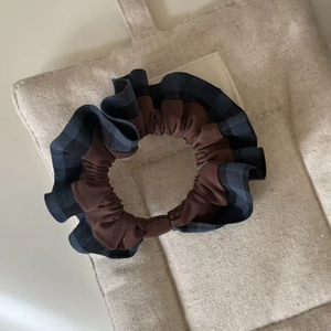 Detailed view of dual-layer plaid scrunchie fabric with navy check pattern and brown inner trim