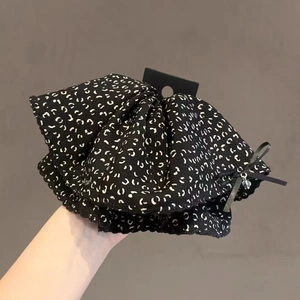 Leopard print scrunchie with bow and silver beads held against a neutral background