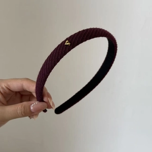 Detail of burgundy knitted headband featuring a small golden heart metal ornament