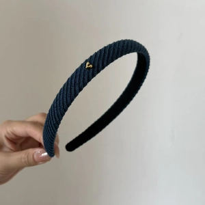 Detailed texture of navy blue knitted headband with a small golden heart charm detail