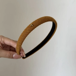 Close-up of brown knitted headband featuring a small golden heart metal detail